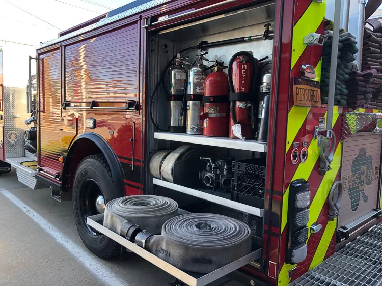 Rear-left profile with open compartments showing extinguishers and equipment bins