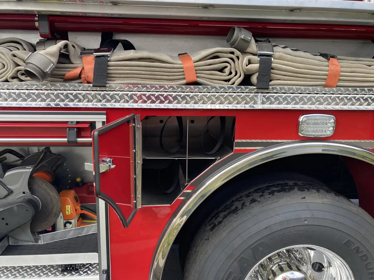 Open compartment close-up showing mounted saw, hand tools, and brackets