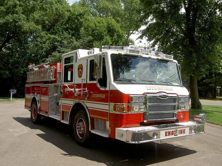 Front right angle showing grille, windshield, bumper-mounted fittings, and side compartment doors.