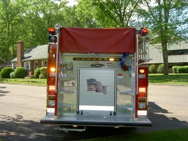 Rear view showing rear roll-up door, warning lights, and hosebed cover