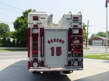 Straight rear view showing rear roll-up door, stacked warning lights, and rear step bumper.