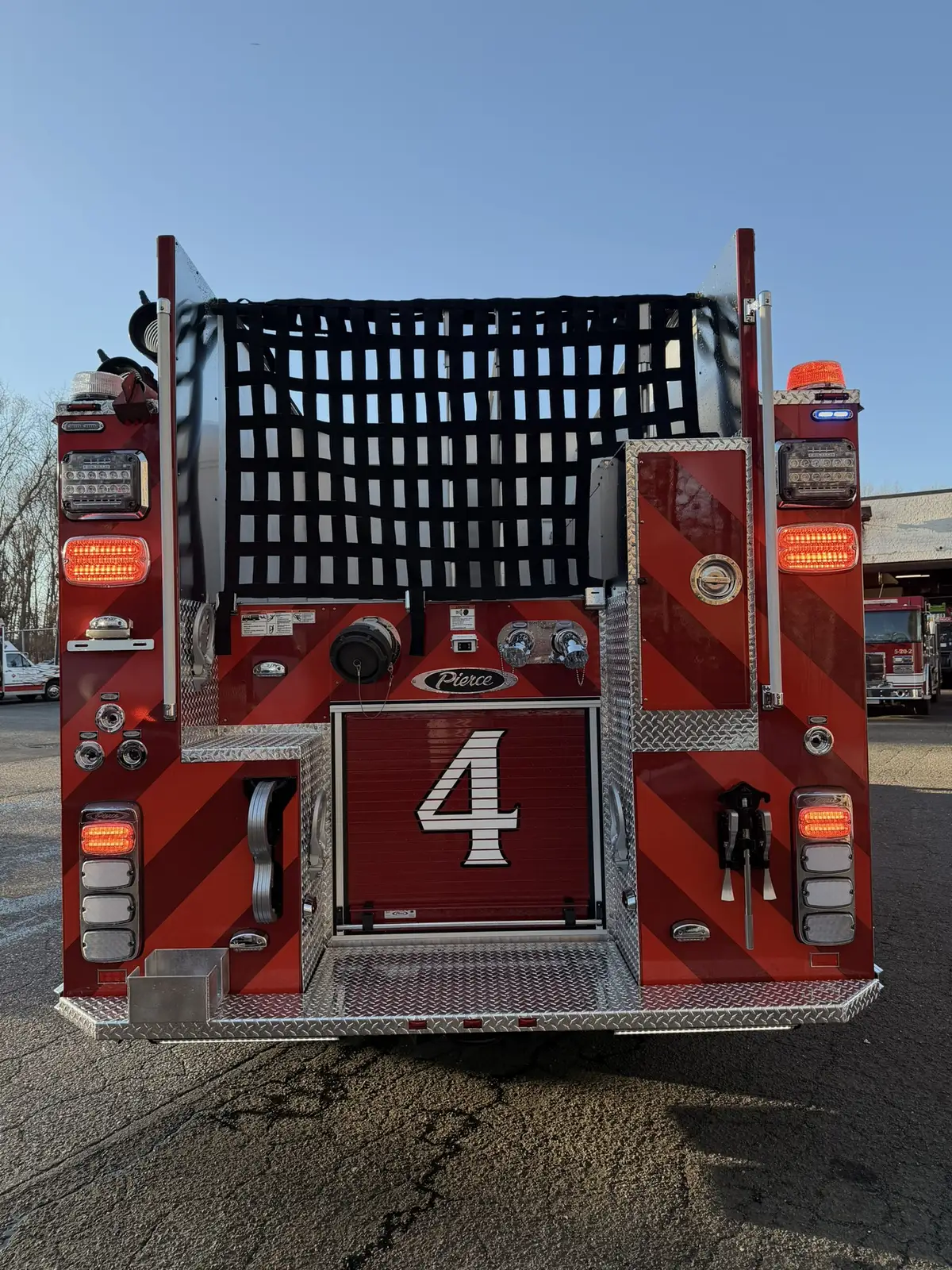 Rear view showing black-and-red chevrons, rear lights, and hosebed netting