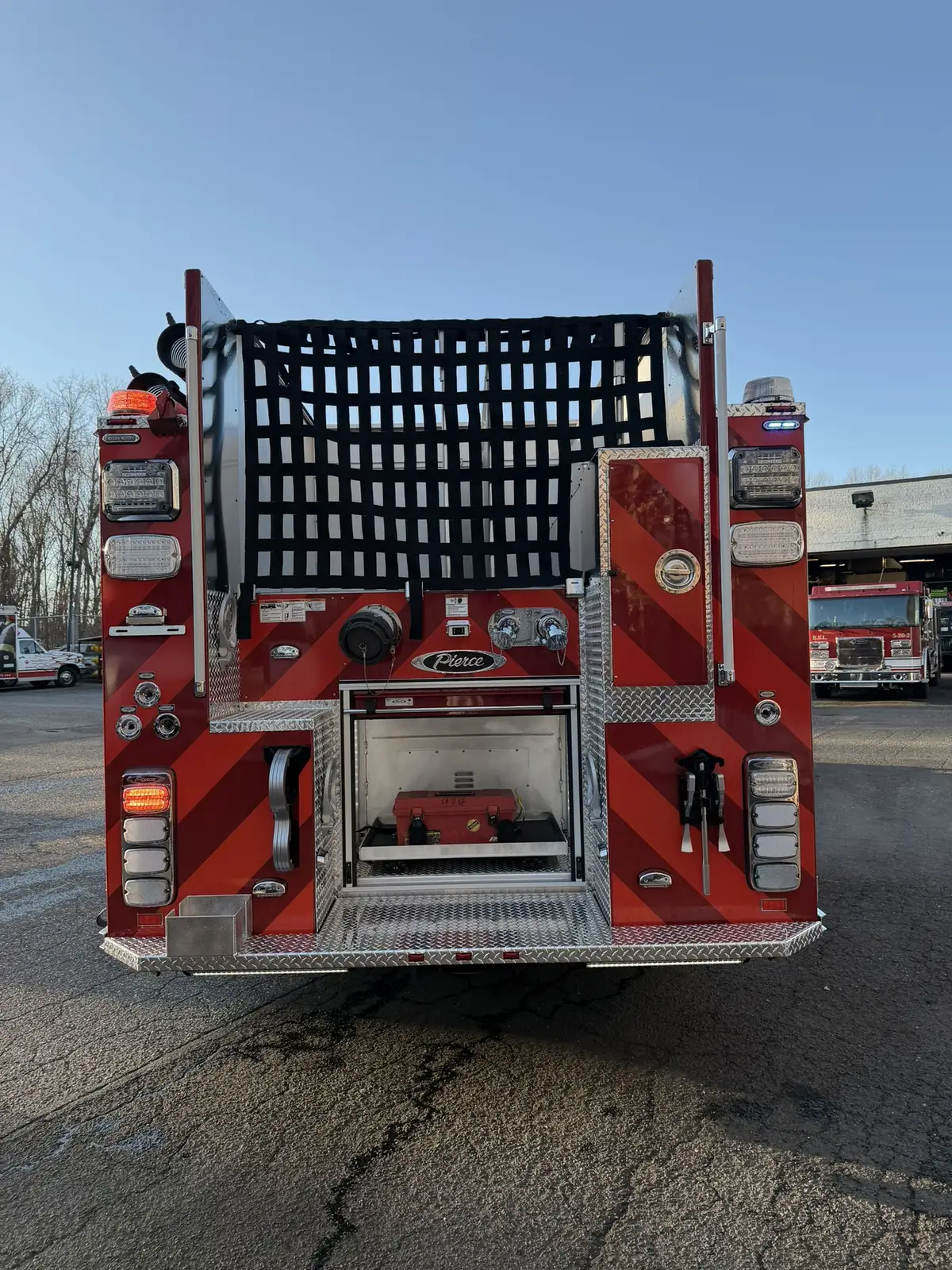 Rear view showing chevron striping, warning lights, and hosebed netting