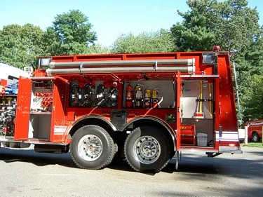 Driver-side rear compartment view showing open equipment bay with hose and tools