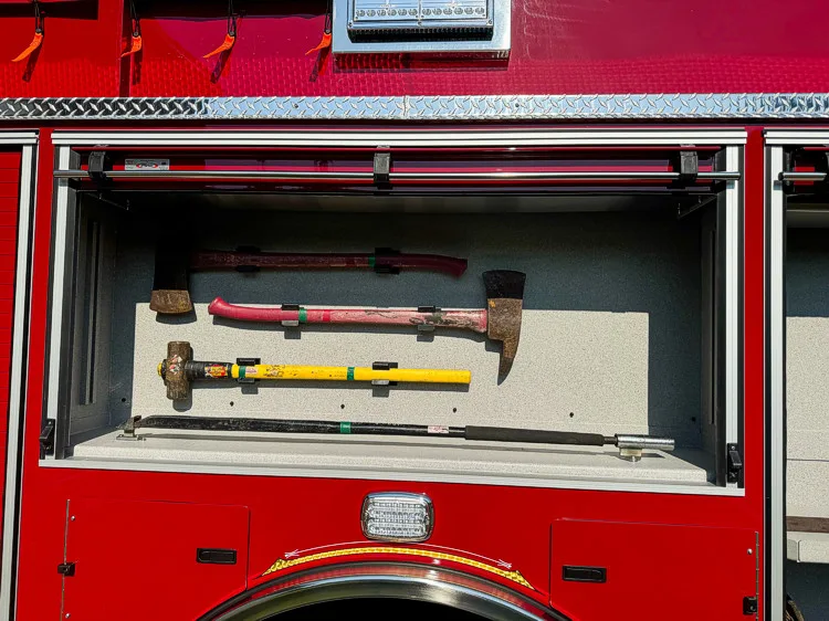 Close-up of a side tool compartment above the rear wheel with mounted striking and prying tools.