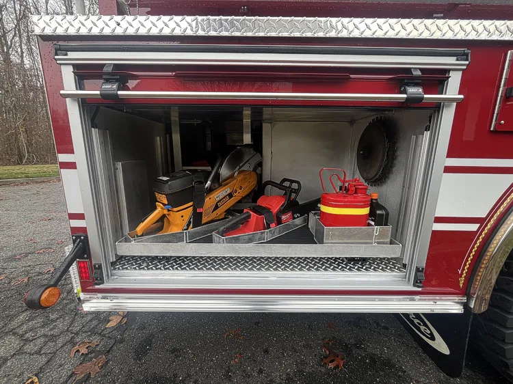 Open side compartment showing rescue tools and equipment cases on shelf
