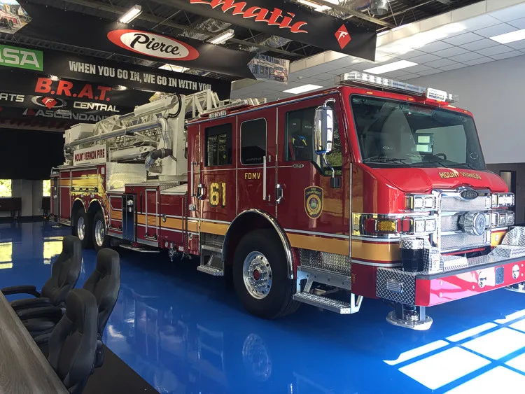 Front right exterior angle showing the cab, front bumper, side compartments, and aerial ladder bed.