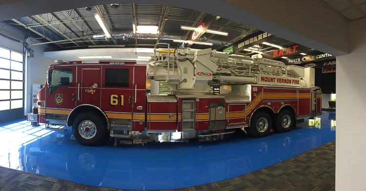 Full left-side profile showing side compartments, tandem axle wheel area, and stowed aerial ladder.