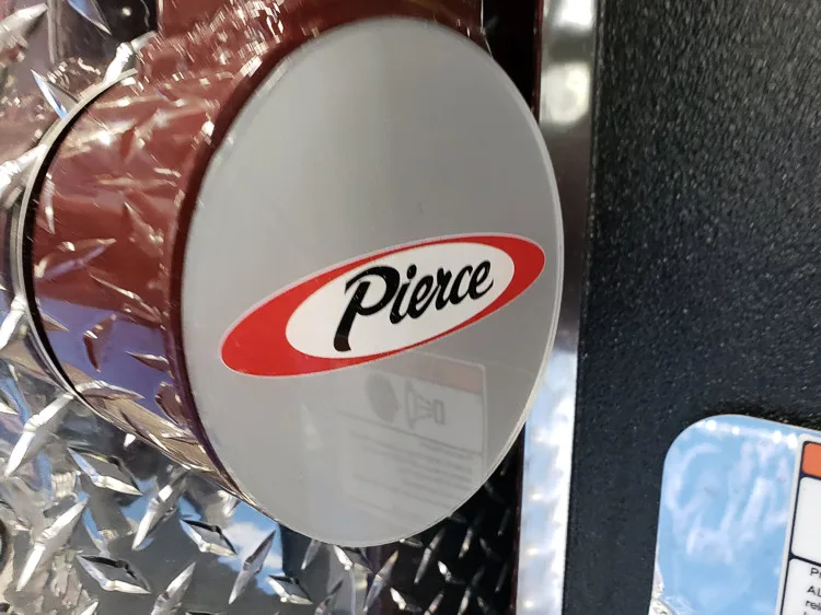 Round Pierce badge close-up mounted on diamond-plate panel