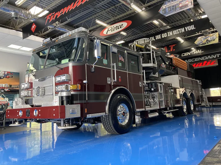 Front-left exterior view showing tower ladder parked in apparatus bay