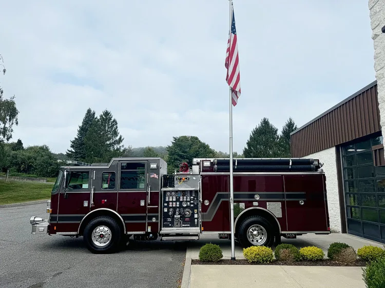 Driver-side profile view with exposed pump panel controls, side compartments, and hose storage along the top.