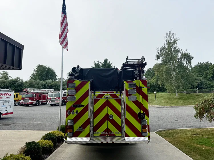 Straight rear view with red-yellow chevrons, rear lights, and covered hosebed section.