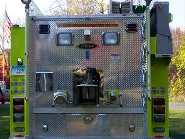 Straight rear view showing rear pump connections, rear lights, and polished diamond-plate paneling.