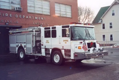 Front right angle showing cab doors, bumper, side pump panel section, and rear body compartments.