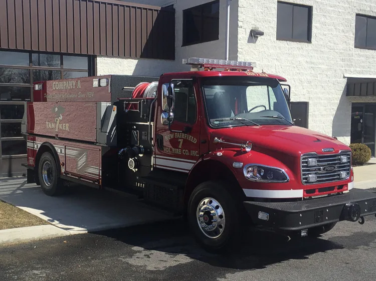 Front right exterior angle showing cab, roof lightbar, side pump controls, and rear tank body.
