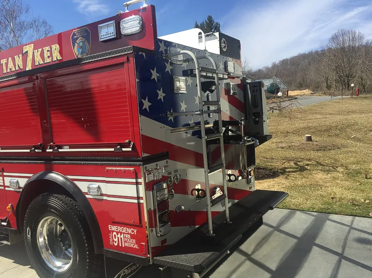 Rear right corner view showing rear ladder, tailboard step, warning lights, and rear connection panel.