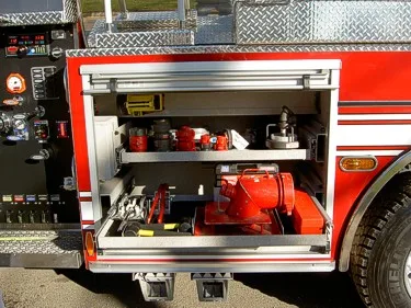 Open side compartment showing intake fittings and portable pump equipment