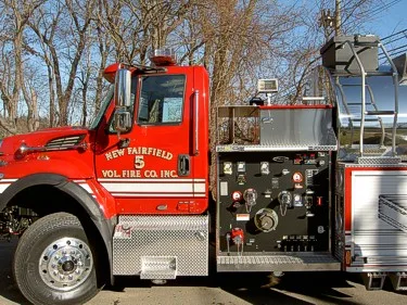 Midship pump panel view showing gauges, valves, and control levers behind cab