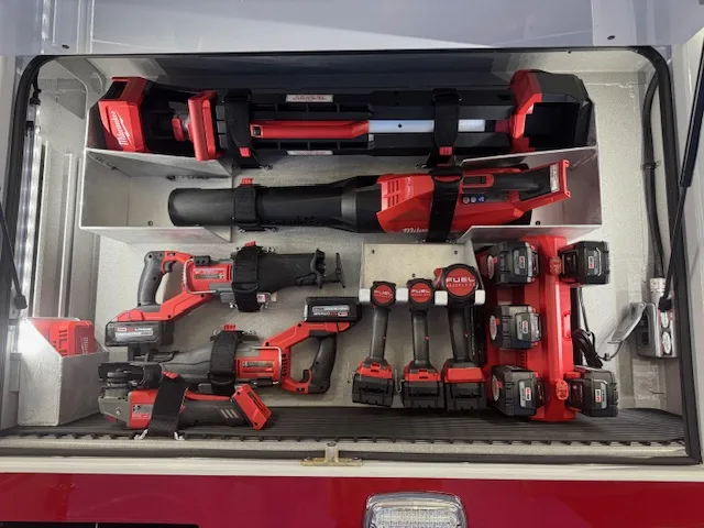 Open compartment close-up showing cordless rescue tools and batteries