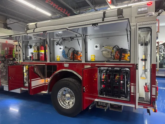 Driver-side rear three-quarter view showing open compartments and rear wheel area