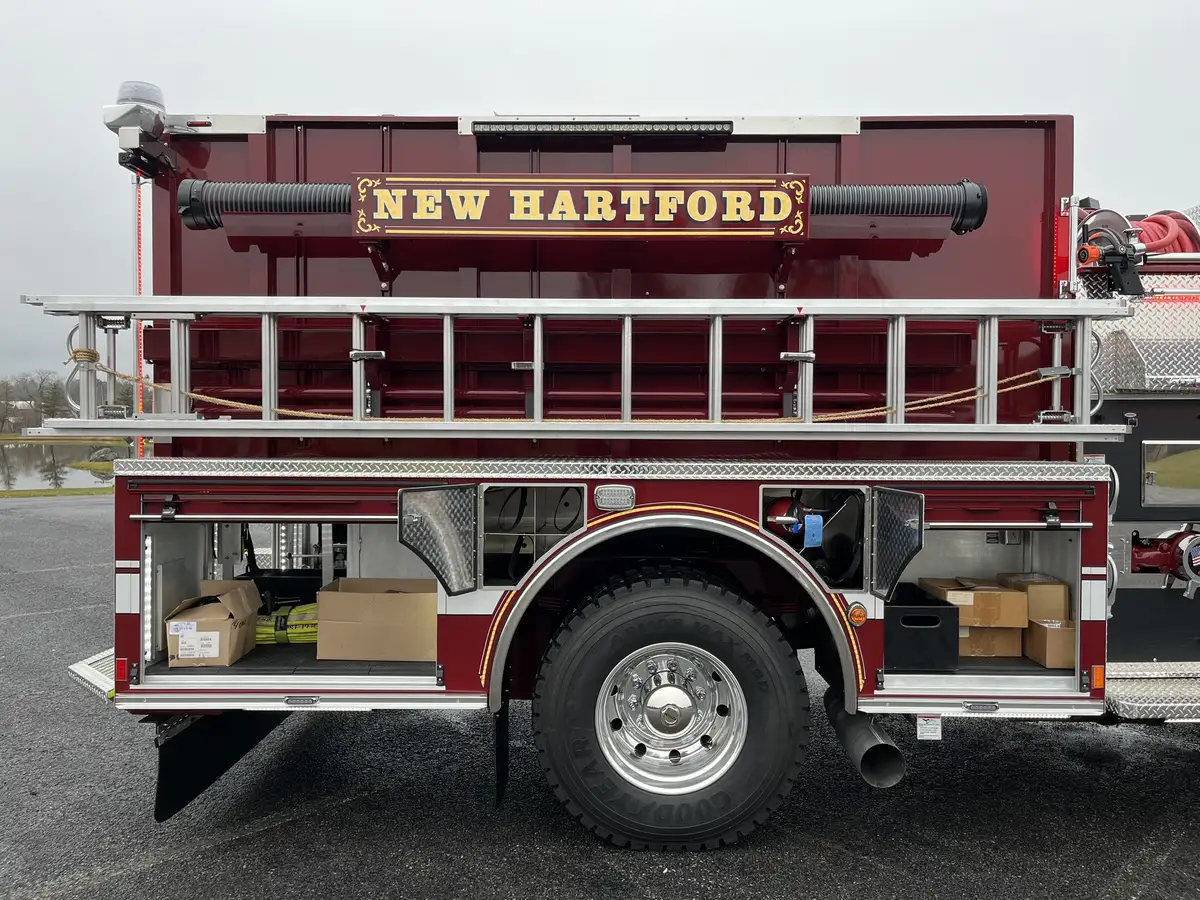 Officer-side profile with open lower compartments, roof ladder, and rear wheel