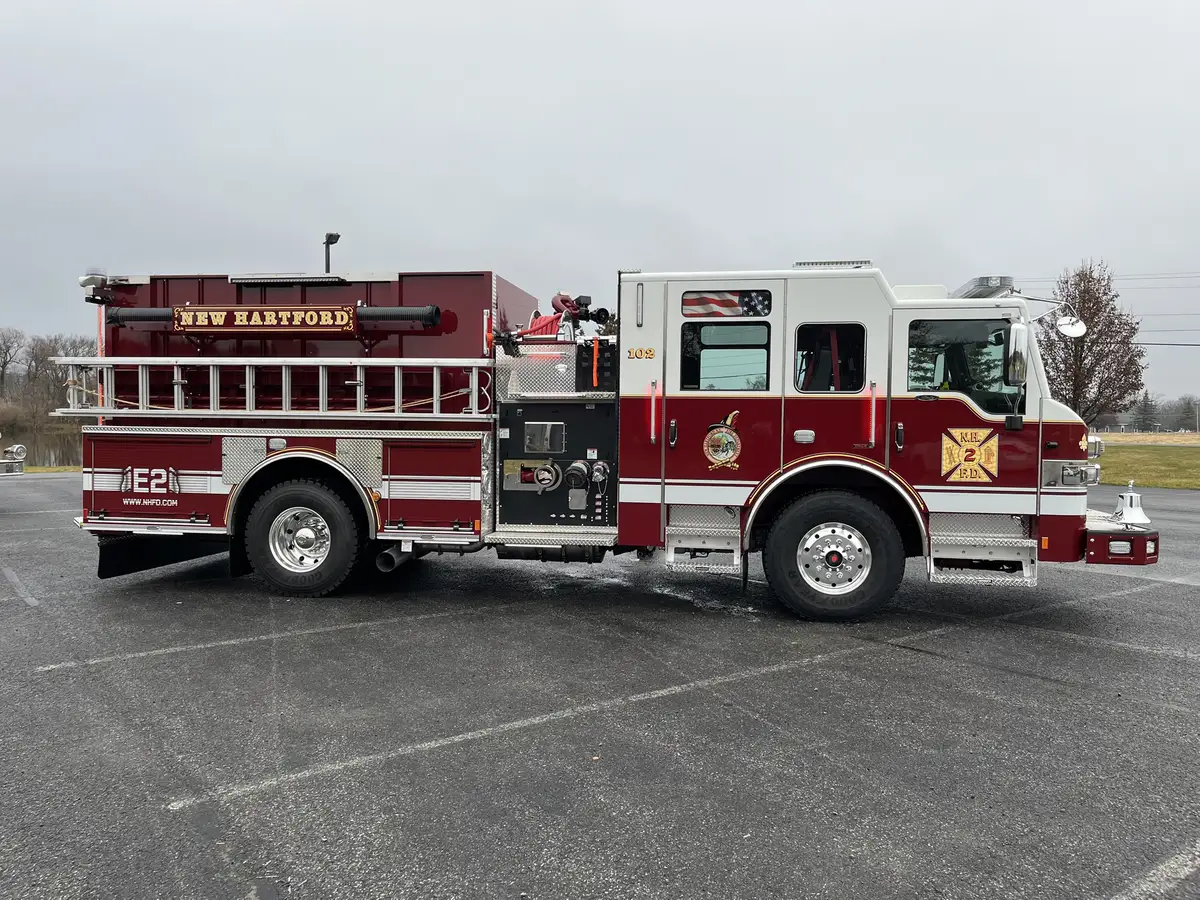 Officer-side full profile view showing pumper body, roof ladder, and rear wheel