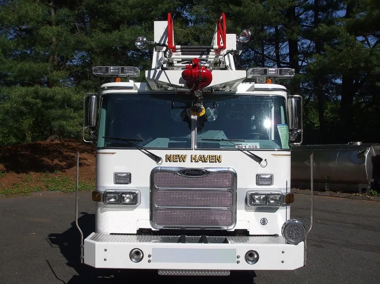 Head-on front view showing grille, windshield, warning lights, and front-mounted aerial nozzle assembly.