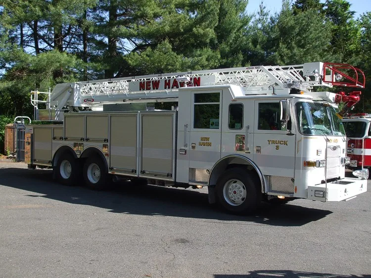 Driver-side full profile showing the stowed aerial ladder, side compartments, and tandem wheel area.