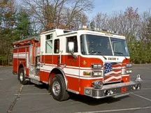 Wide front right view of the parked pumper showing bumper, cab, and side compartments.