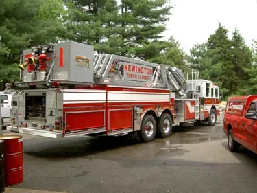 Rear left side view showing long body compartments, stowed aerial, and tandem rear wheels.