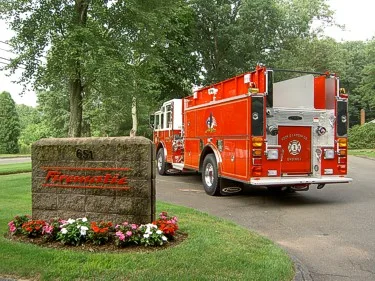 Rear-right exterior view showing pumper parked near stone sign and landscaping