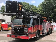Pierce Ascendant tower ladder front-left view showing bucket, aerial sections, and side compartments