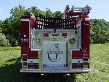 Straight rear view showing rear roll-up door, hosebed netting, warning lights, and tailboard.