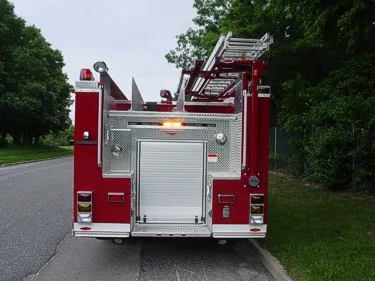 Straight rear view showing rear roll-up door, hosebed side boards, and tail lights.