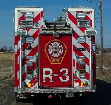 Straight rear view with diagonal striping, rear warning lights, and a large center rear door panel.