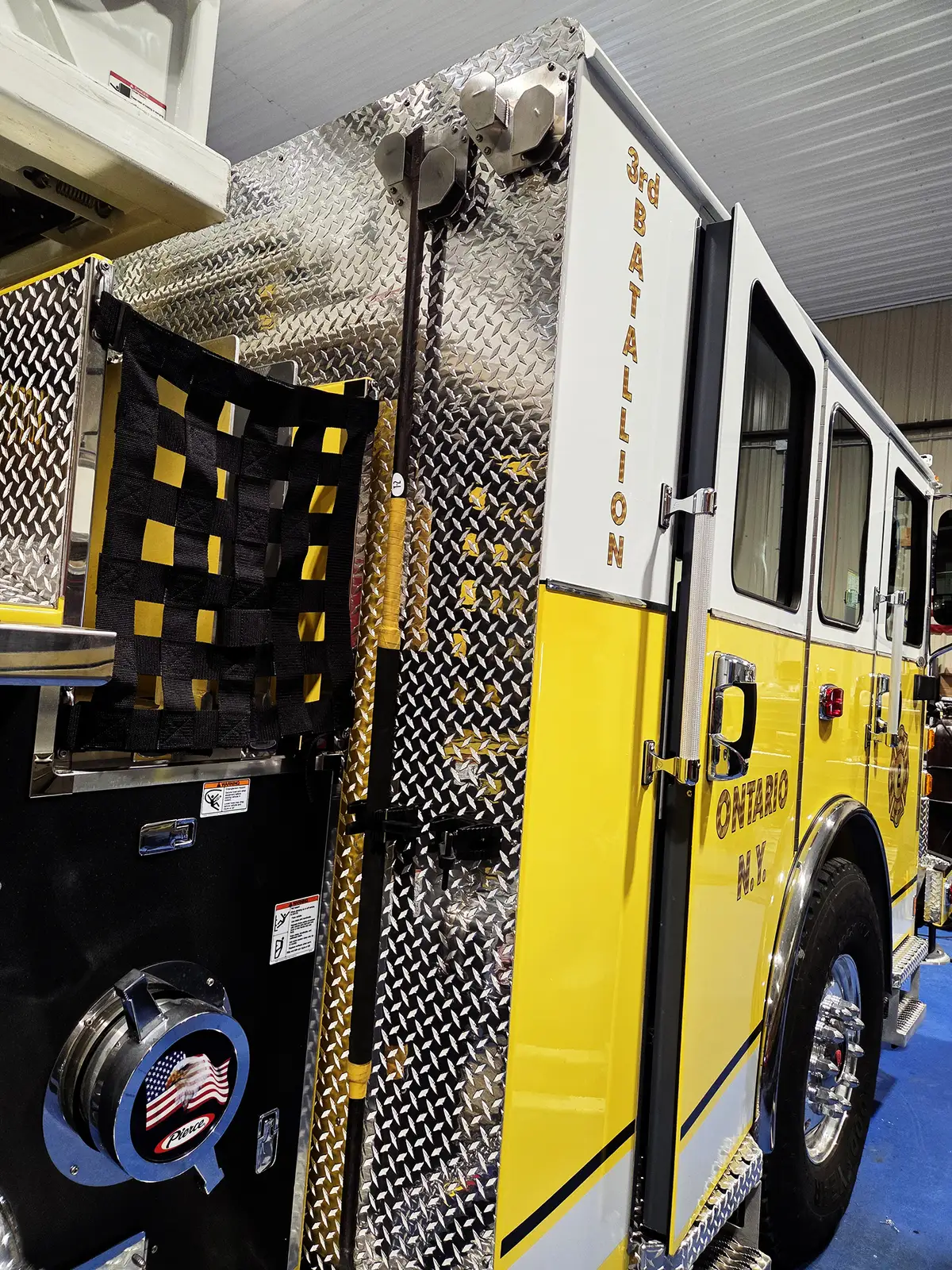 Rear-side body view showing hosebed netting, side access ladder, and open door