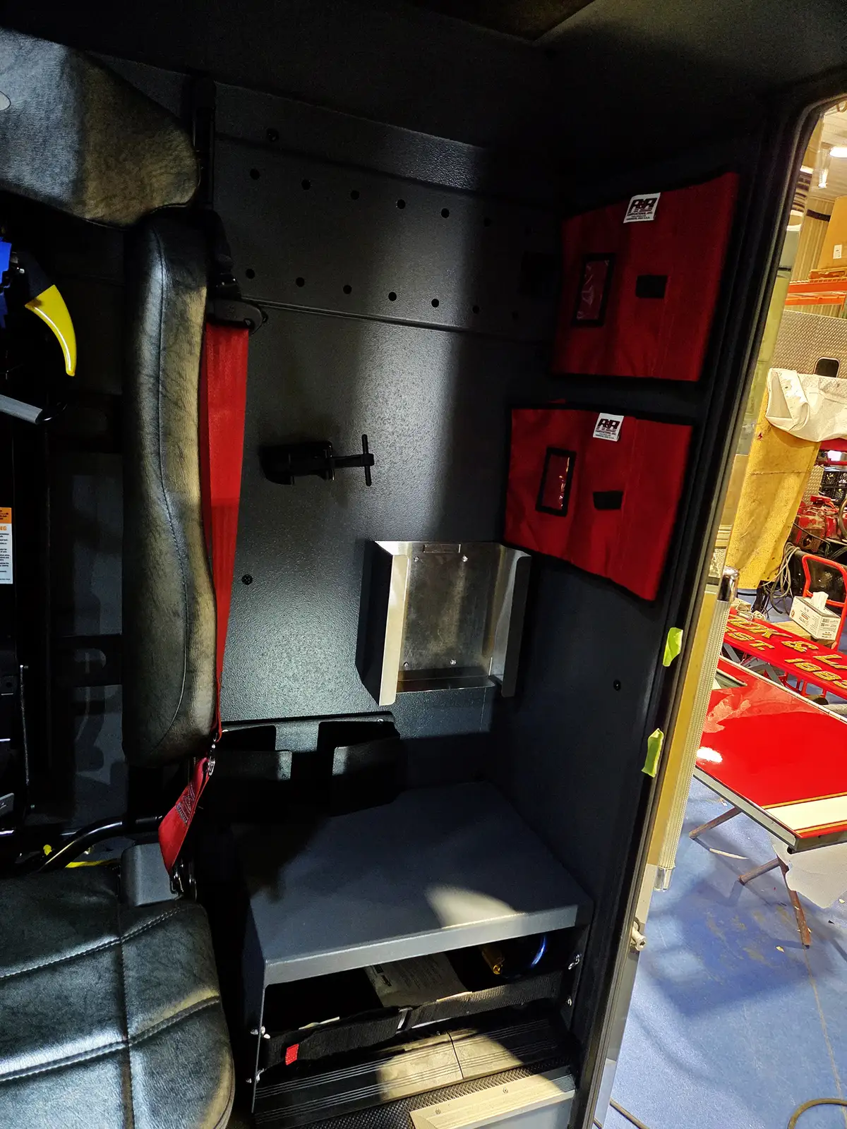 Interior seat-side storage view showing red medical bags and wall mounts