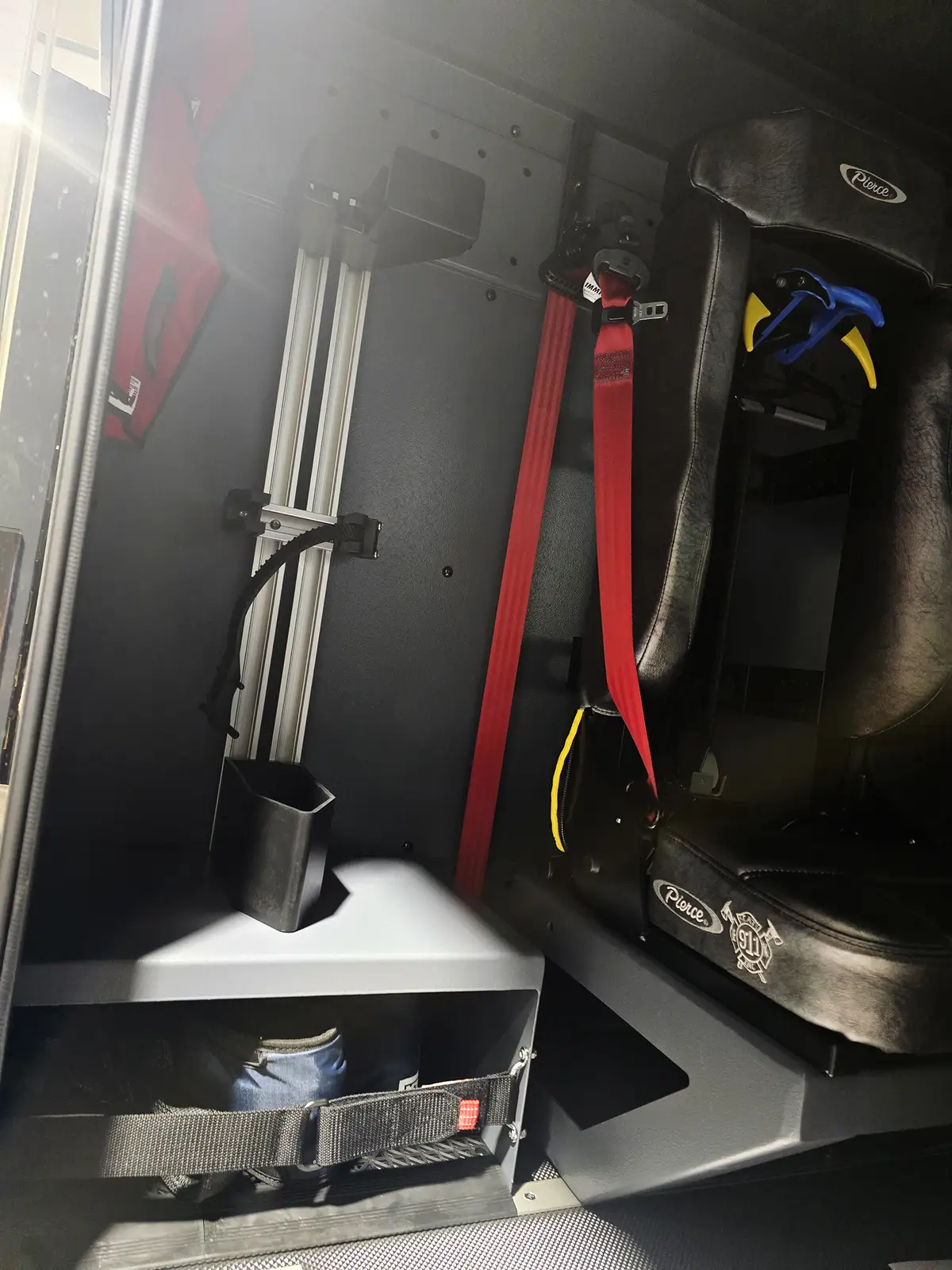 Crew-seat area close-up showing red restraint strap and equipment mounts