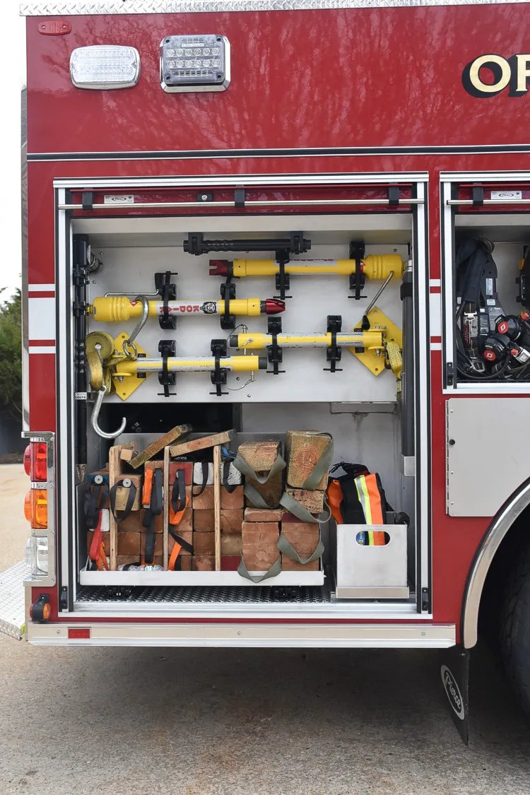 Open side compartment showing shelves with adapters, straps, and utility tools