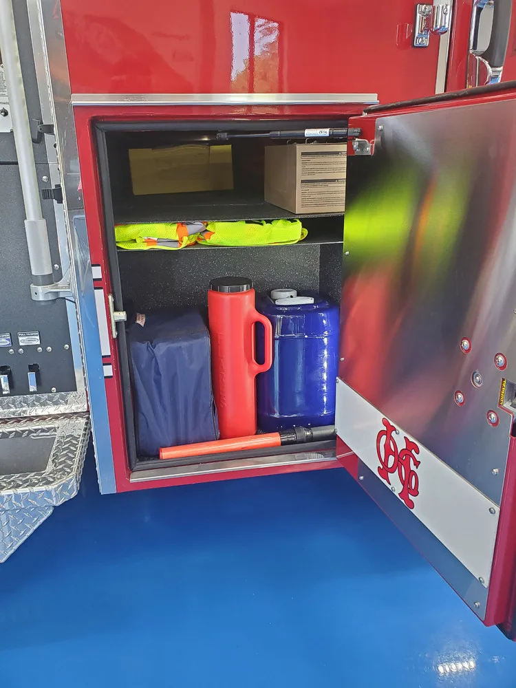 Open compartment showing utility jugs and small equipment bins