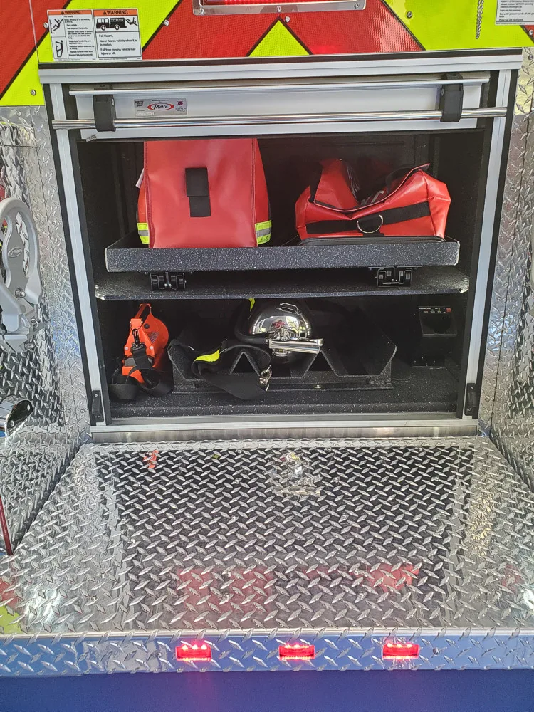 Open rear-side compartment showing shelves with helmets and gear bags