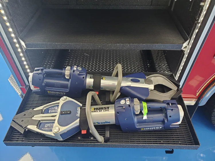 Open lower compartment showing cordless rescue tools and chargers