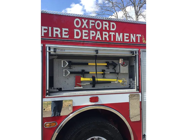 Open side compartment above rear wheel showing mounted hand tools and axe