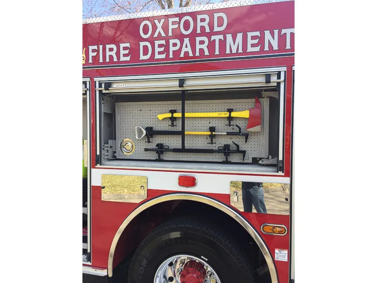 Open side tool-board compartment showing pike poles and shovels over rear wheel area