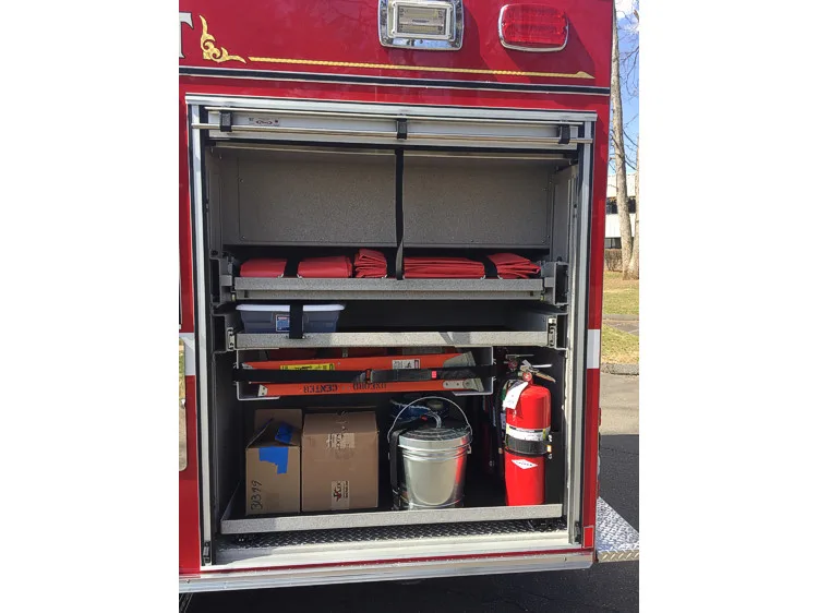 Open rear-side compartment showing folded hose, fire extinguisher, and tool storage