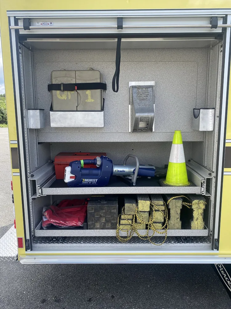 Open side compartment showing bag storage and traffic cone on lower shelf