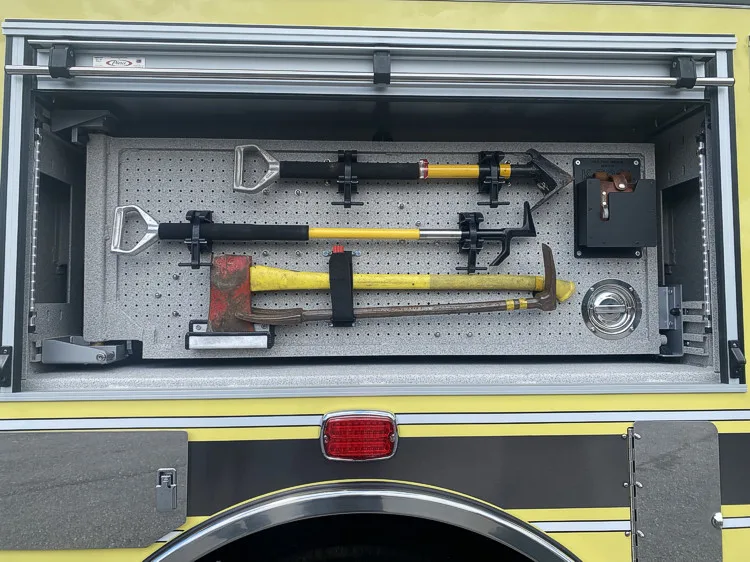 Open side compartment showing mounted hand tools and pike poles