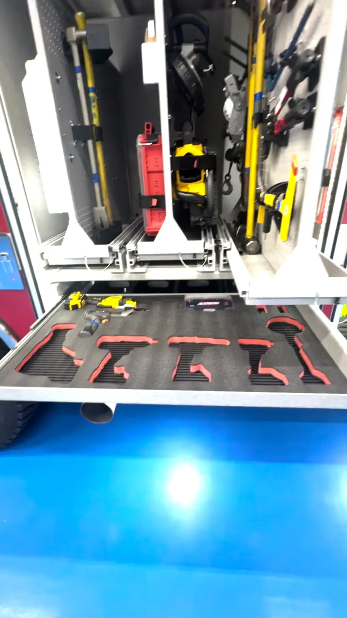 Open compartment with slide-out tray showing mounted tools and storage channels