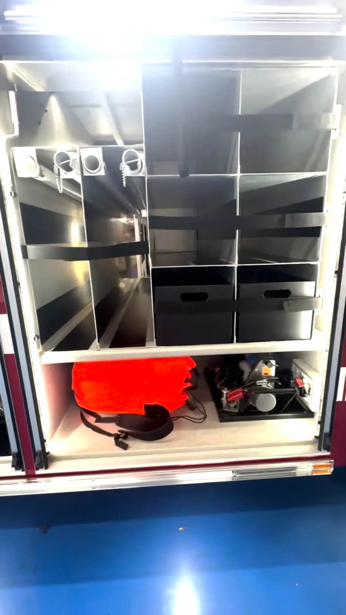 Open compartment showing divided shelving, black bins, and lower gear storage