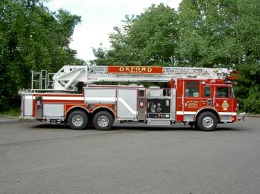 Driver-side full profile showing ladder bed, pump panel area, and tandem rear axles